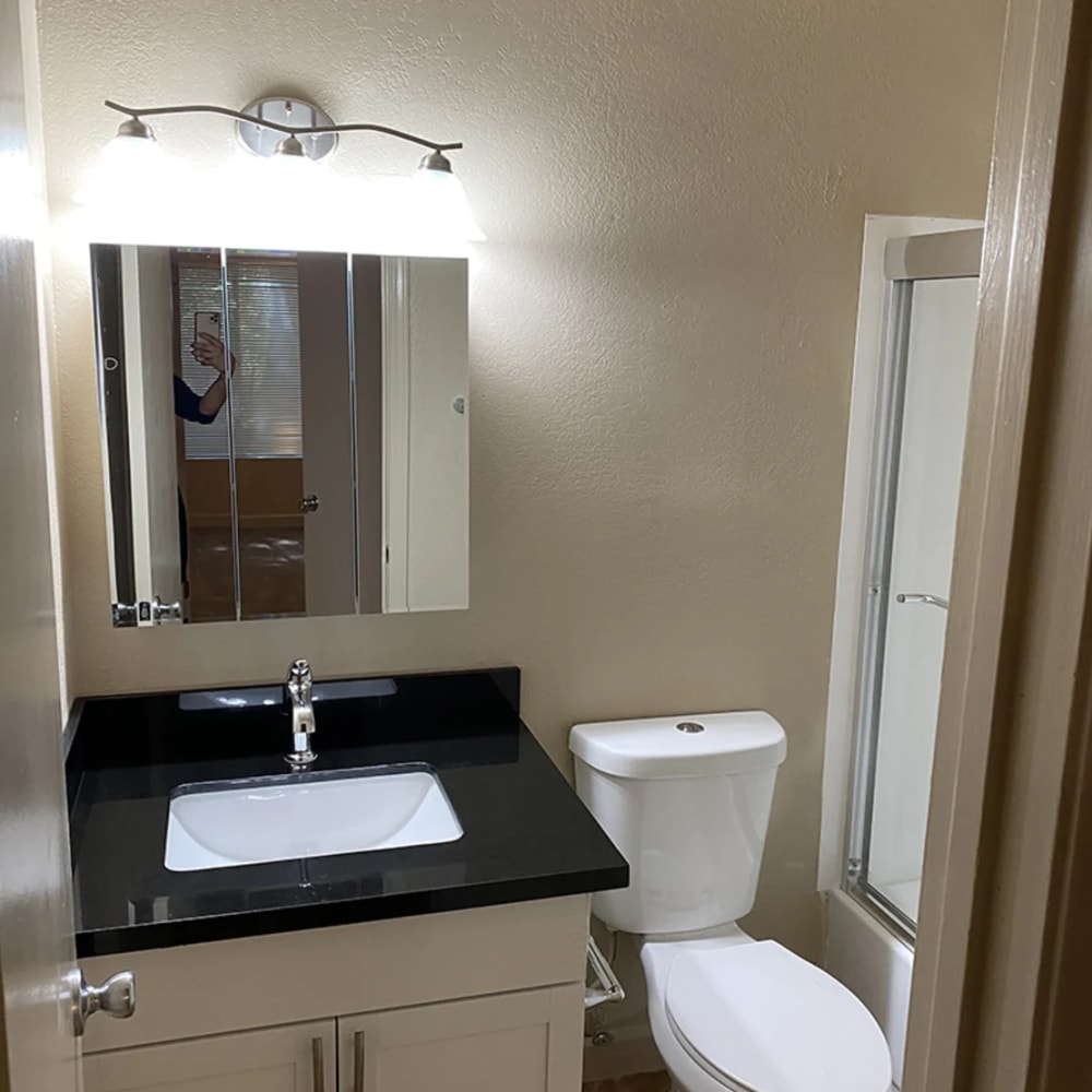 Bathroom with white cabinetry and dark countertop at Iron Horse Apartments in Stockton, California
