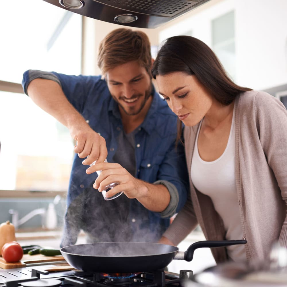 Happy couple cooking in kitchen at Wadsworth Park Apartments in Los Angeles, California
