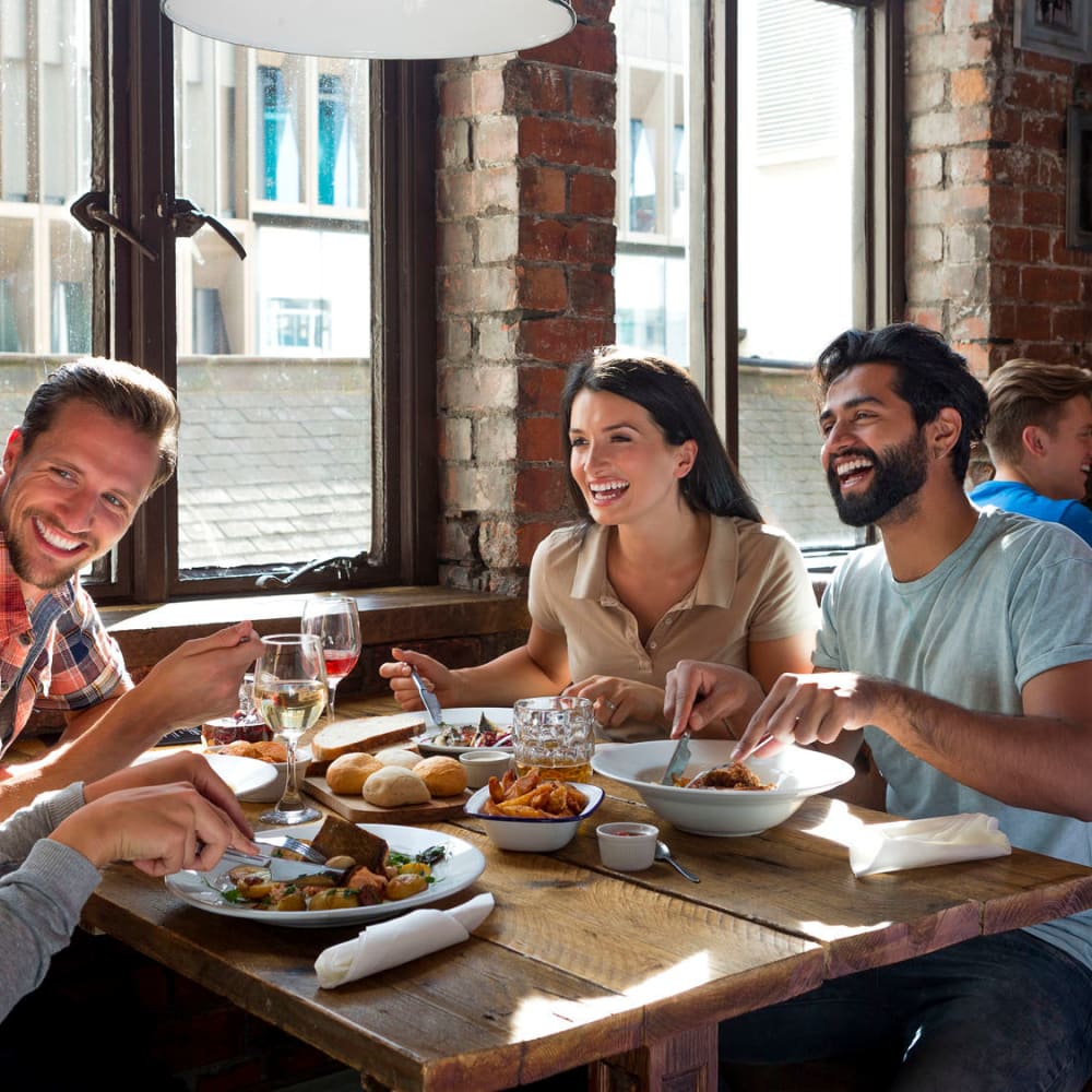 Happy friends enjoying food at restaurant near Wadsworth Park Apartments in Los Angeles, California
