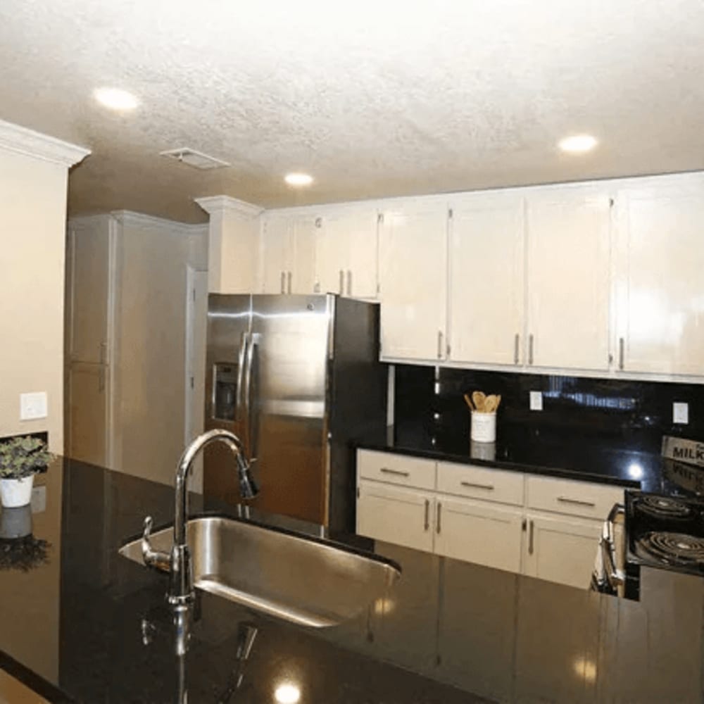 Kitchen with wood-style flooring, granite countertops, and stainless-steel appliances at Quailwood Apartments in Stockton, California