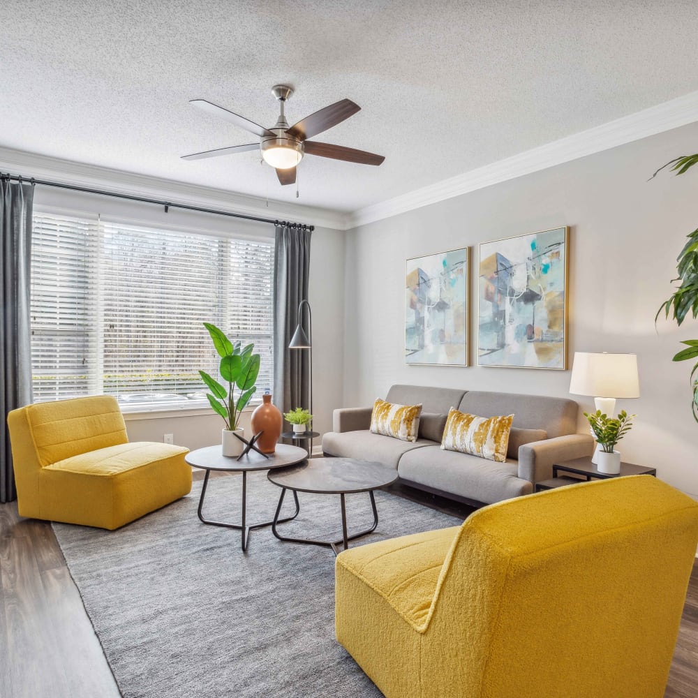 Living room with large windows and a ceiling fan in a model apartment at Hawthorne Gates in Atlanta, Georgia