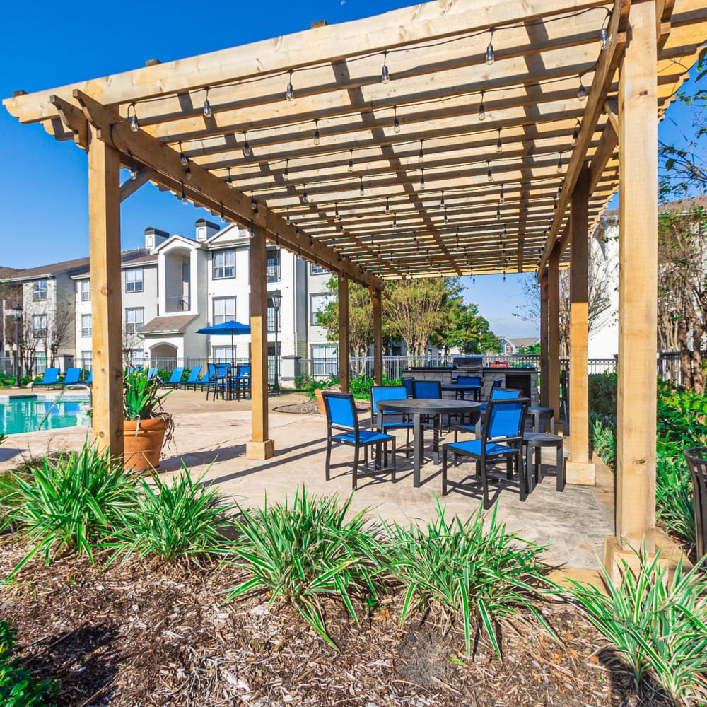 A covered outdoor seating area beside the pool at Discovery at West Road in Houston, Texas