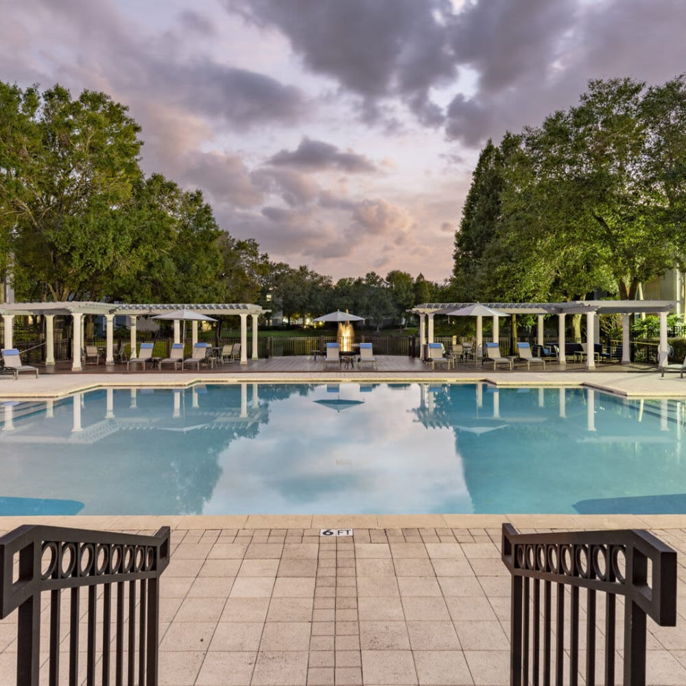Covered patio seating and picnic tables surround the pool at Sabal Palm in Tampa, Florida