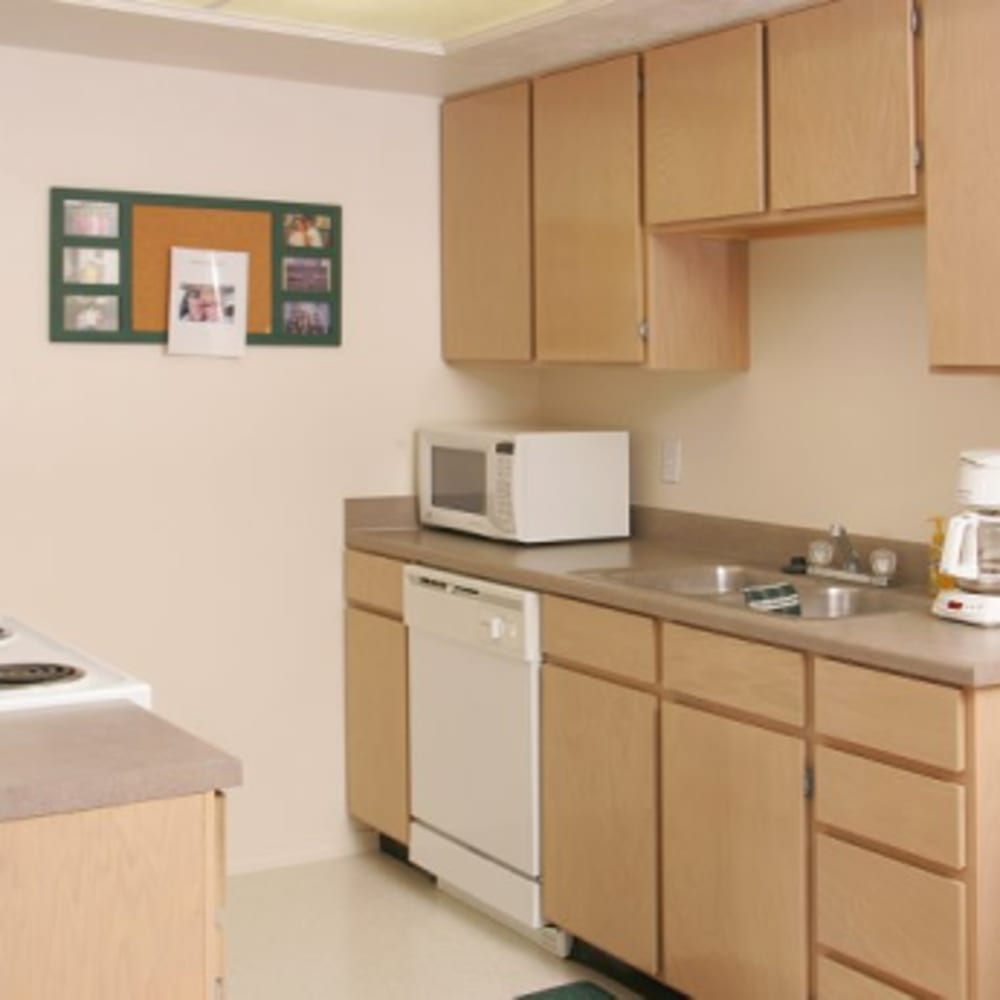 Light wood cabinets and white appliances in an apartment kitchen at Clinton Towne Center Apartments in Clinton, Utah