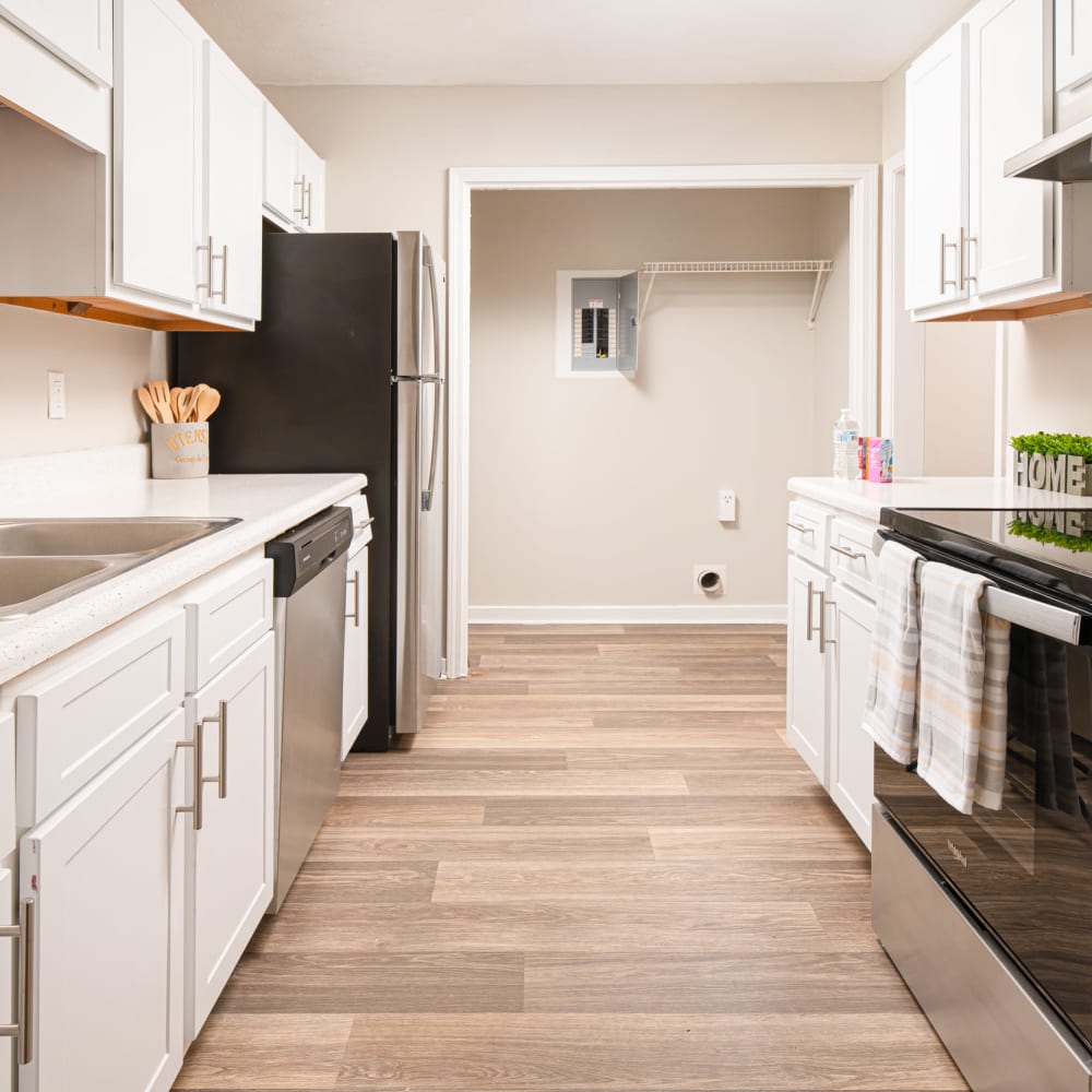 Spacious kitchen with wood flooring and whit cabinetry in a model home at Bradford Place Apartments in Byram, Mississippi