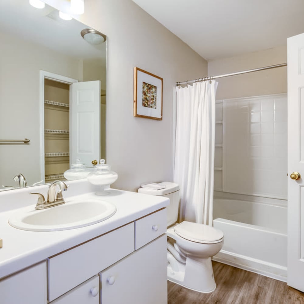 White cabinets and a full-sized bathtub in an apartment bathroom at Spring Lake in Byram, Mississippi