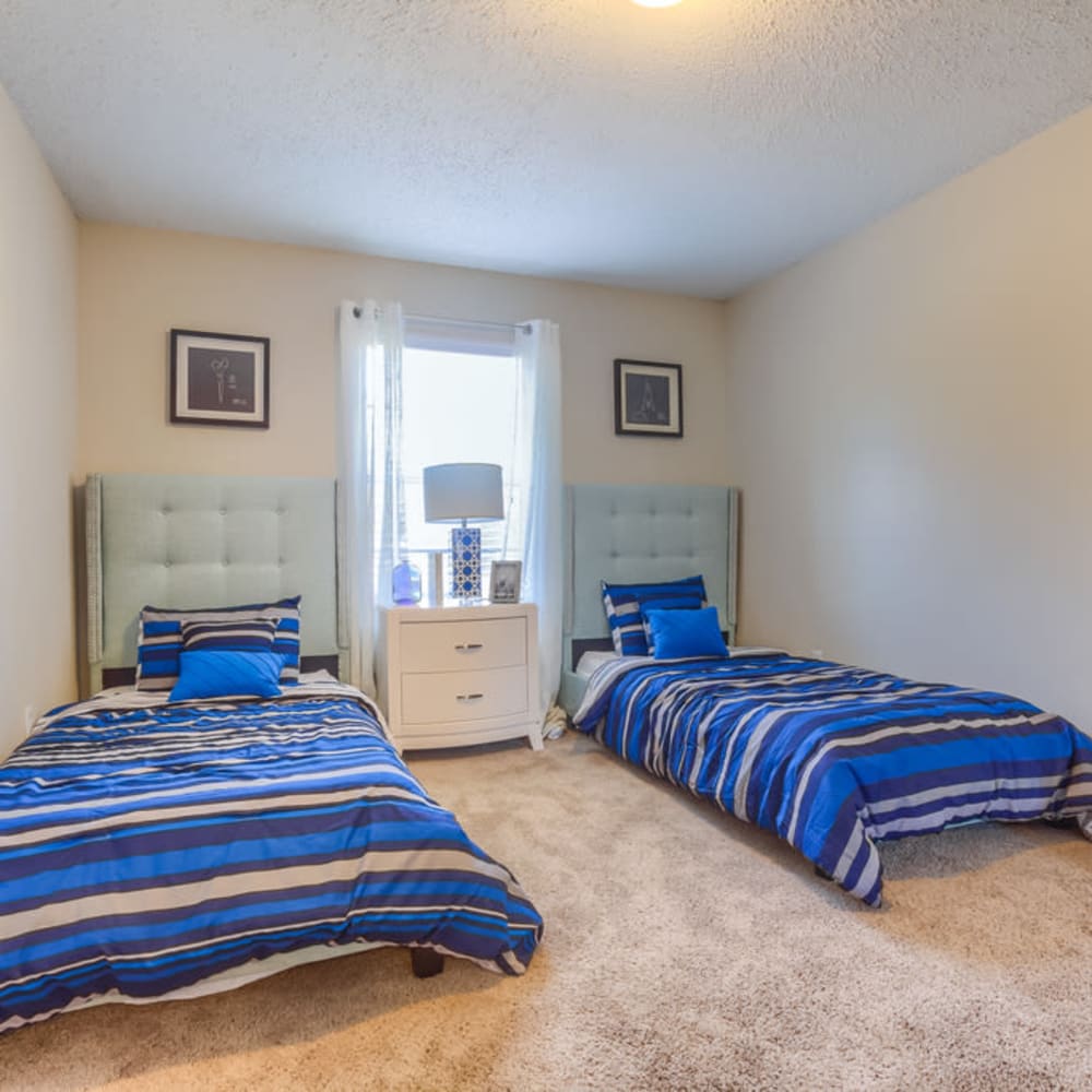 A spacious bedroom with two twin beds in an apartment at Northbrook & Pinebrook in Ridgeland, Mississippi