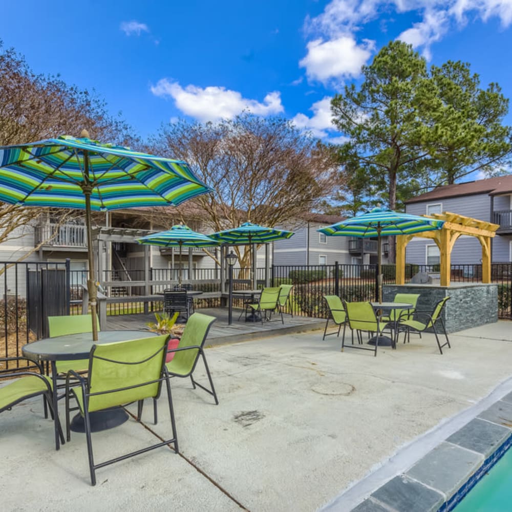Tables and outdoor seating under umbrellas next to the swimming pool at Northbrook & Pinebrook in Ridgeland, Mississippi