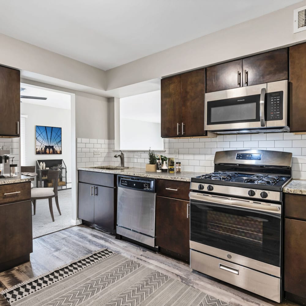 Dark wood cabinets and stainless-steel appliances in an apartment kitchen at Huntington Apartments in Naperville, Illinois