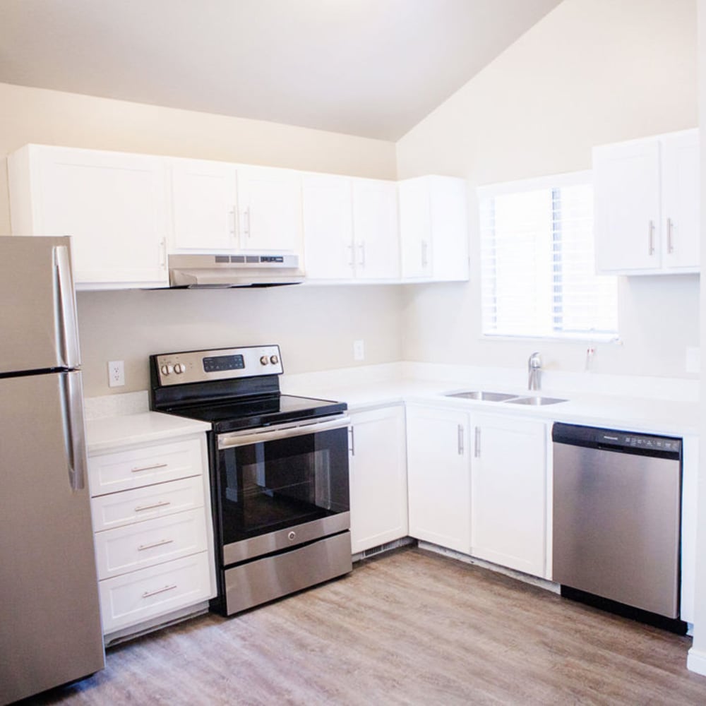 Model kitchen with white cabinets and wood flooring at The Franklyn Apartments in Millcreek, Utah