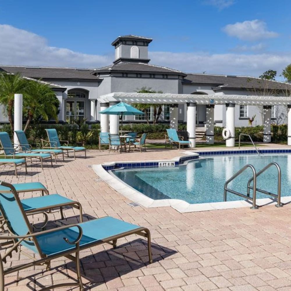 Resort-style pool with pool chairs and covered tables and chairs at The Fairways at Lake Mary in Lake Mary, Florida