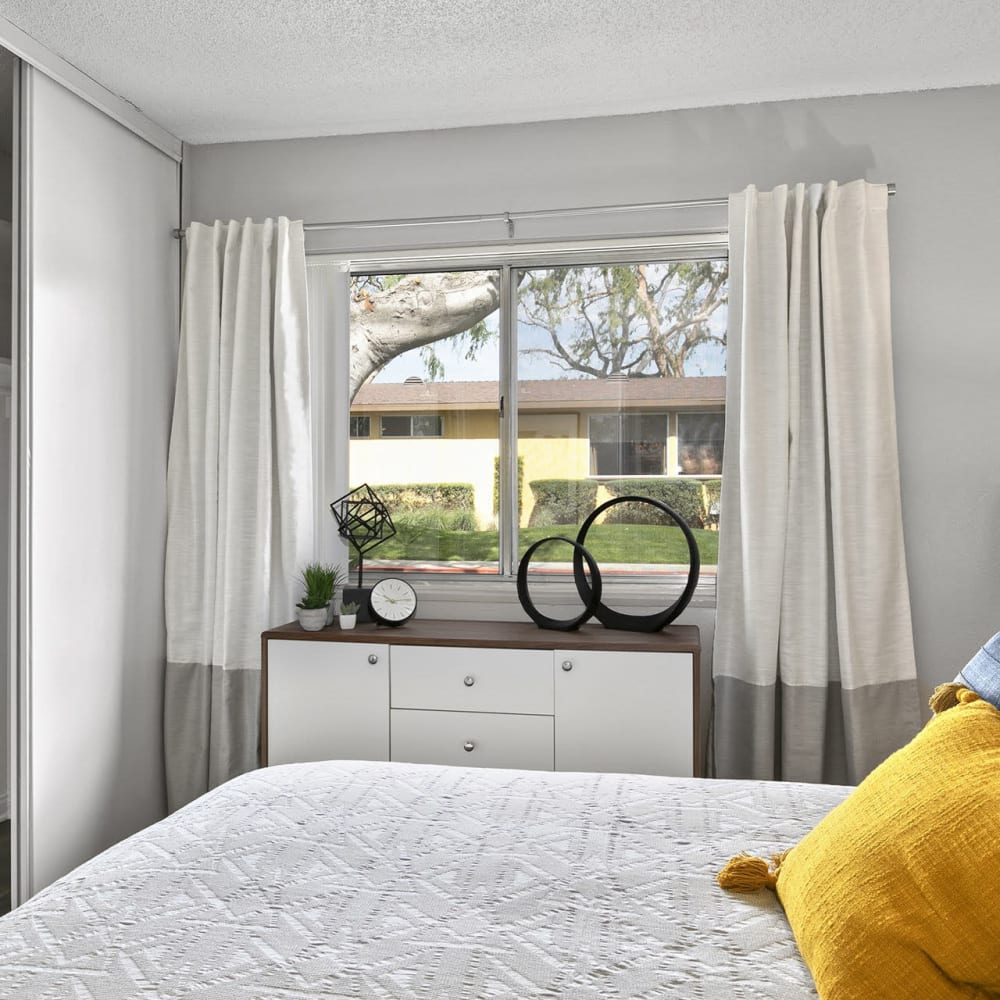 Bedroom with large windows at Casitas Apartments in Ontario, California