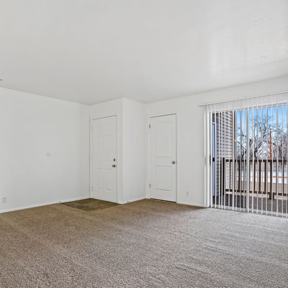 An apartment living room with a sliding door to the balcony at Chadds Ford Apartments in Midvale, Utah