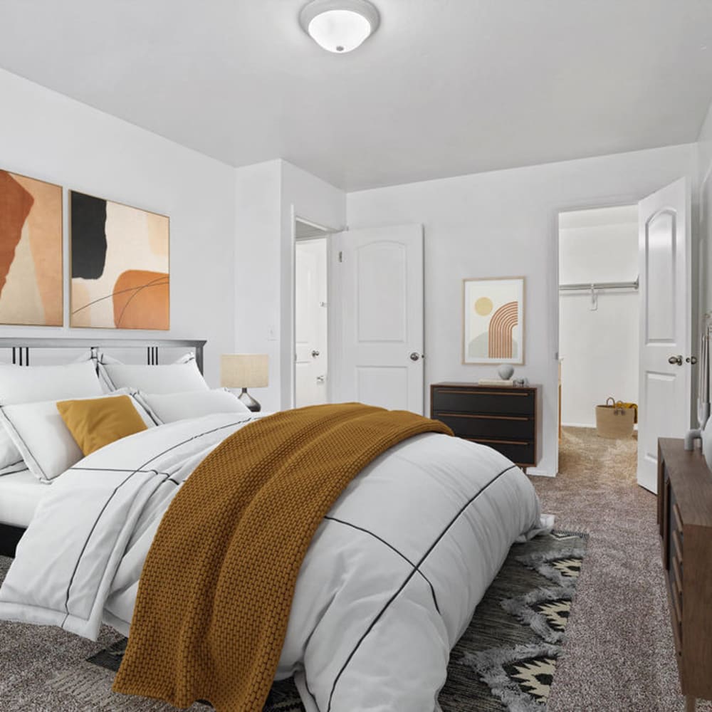 A furnished apartment bedroom with the closet door open at Chadds Ford Apartments in Midvale, Utah