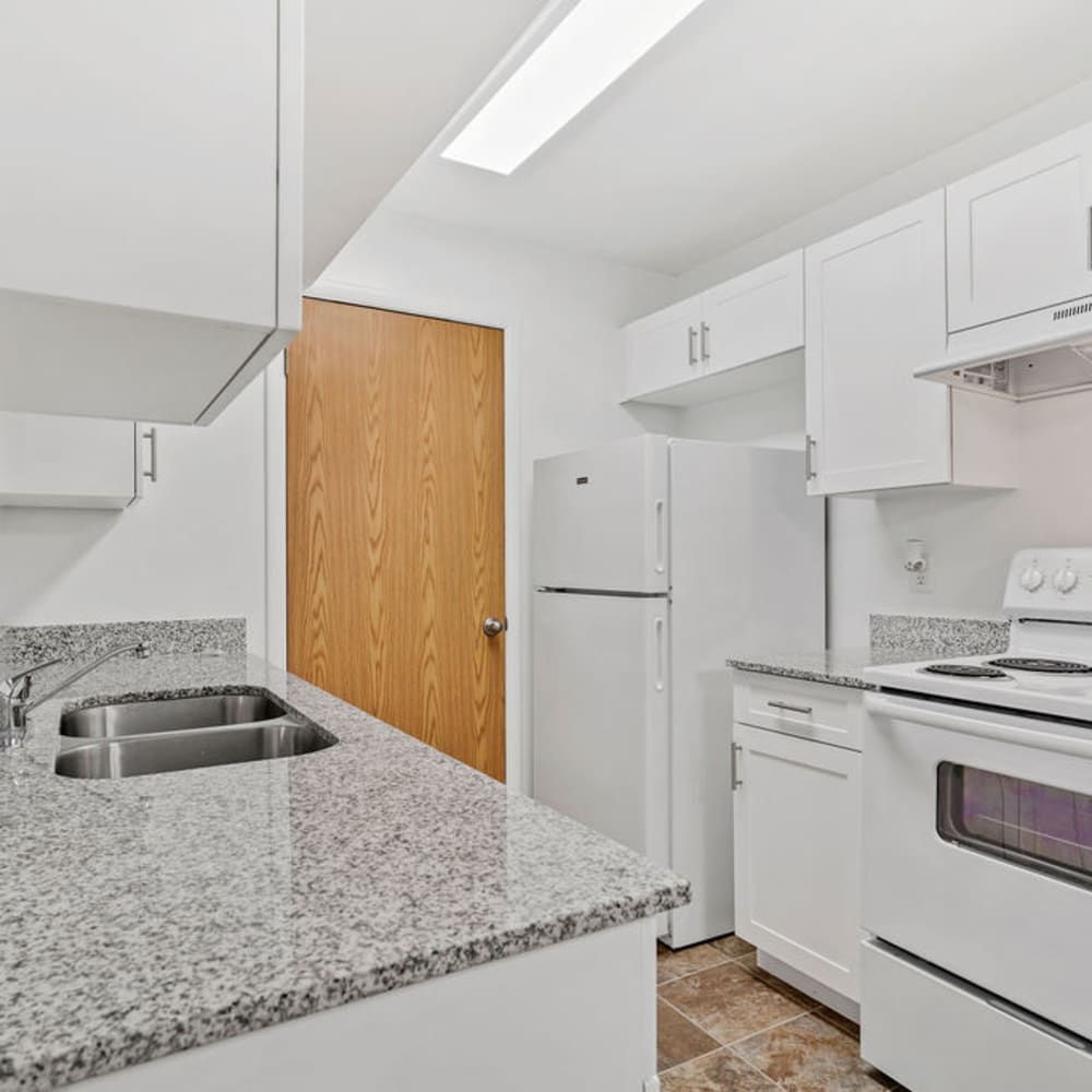 Wood cabinets and white appliances in an apartment kitchen at Lincoln Park Apartments in Taylorsville, Utah