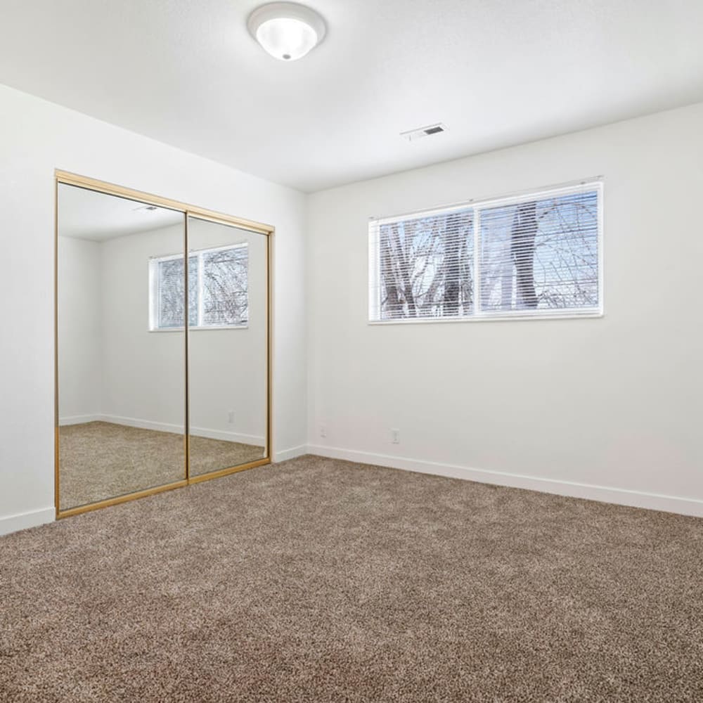 An apartment bedroom with mirrored closet doors at Mark Twain Apartments in Salt Lake City, Utah