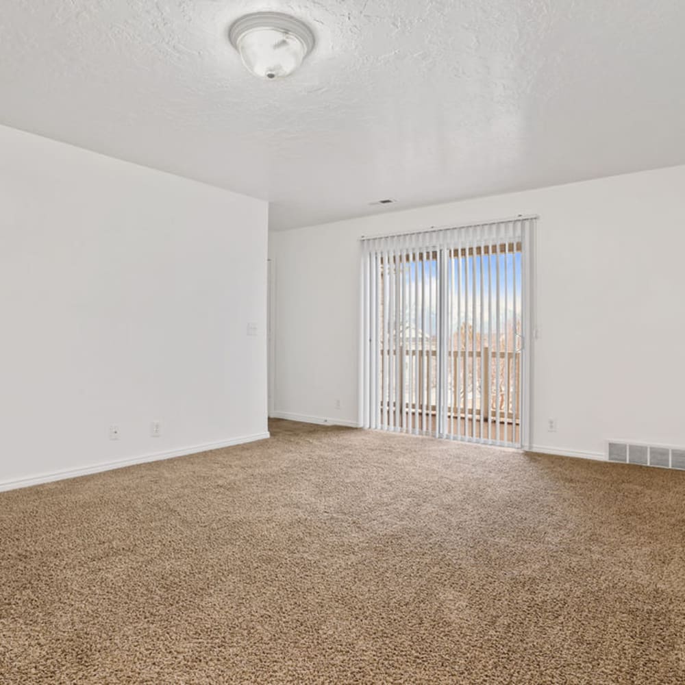 Plush carpeting in an apartment living room with a sliding door to the balcony at Stonebridge Apartments in West Jordan, Utah