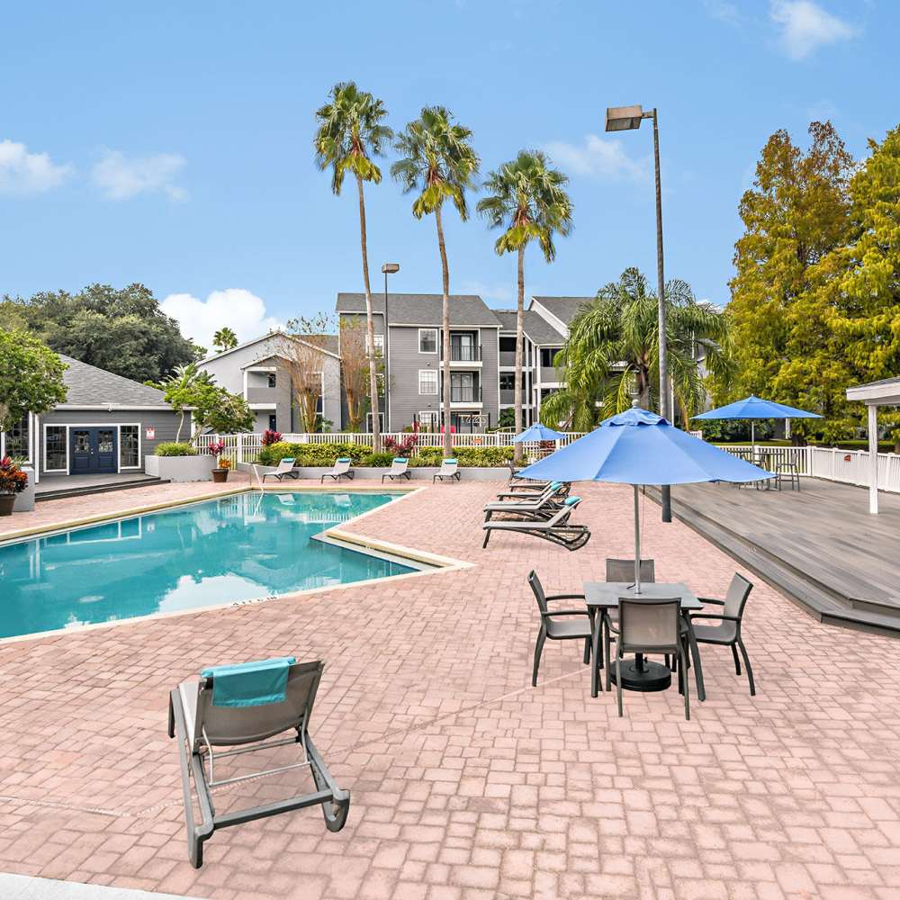 Swimming pool area with tables and lounge chairs at Fourteen01 Apartments in Orlando, Florida