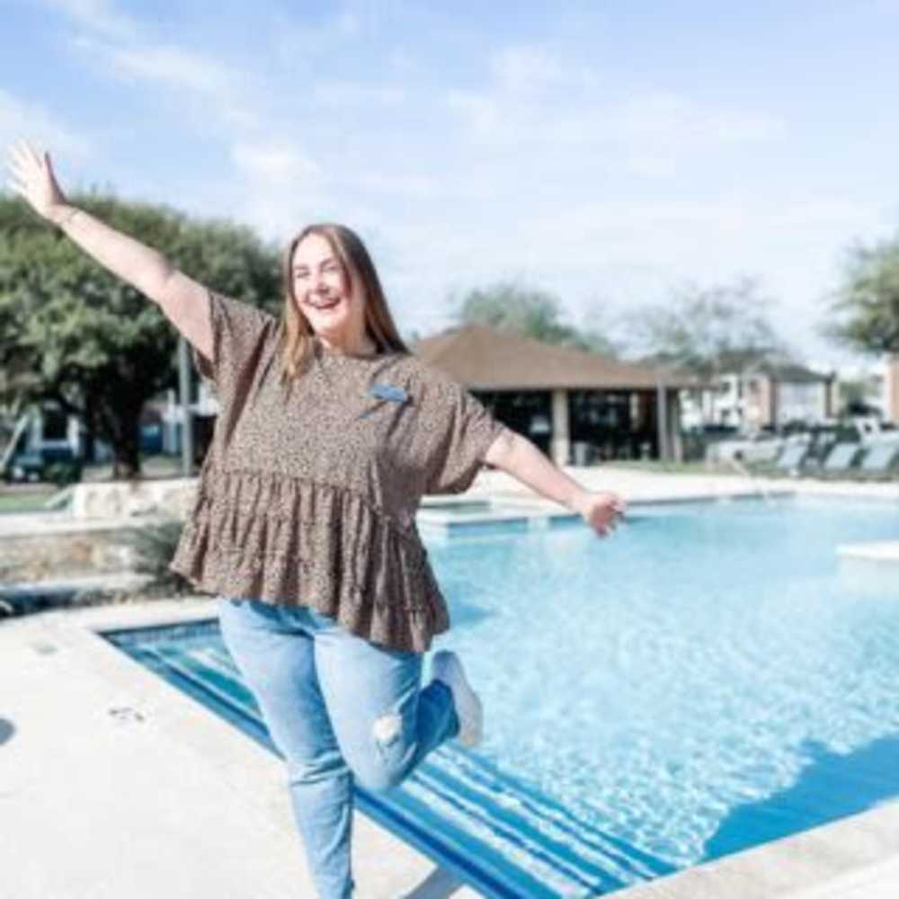 Resident posing by the pool at The Landing at College Station in College Station, Texas