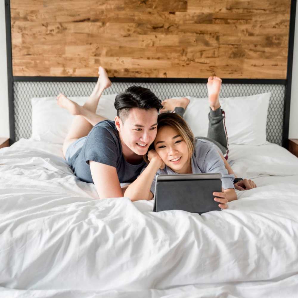 Happy couple watching movie on iPad in their new bedroom at High Rock in Sparks, Nevada