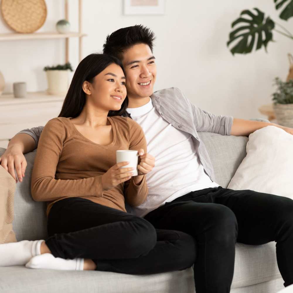 Happy couple in living room at 353 Main Street Family Apartments in Redwood City, California