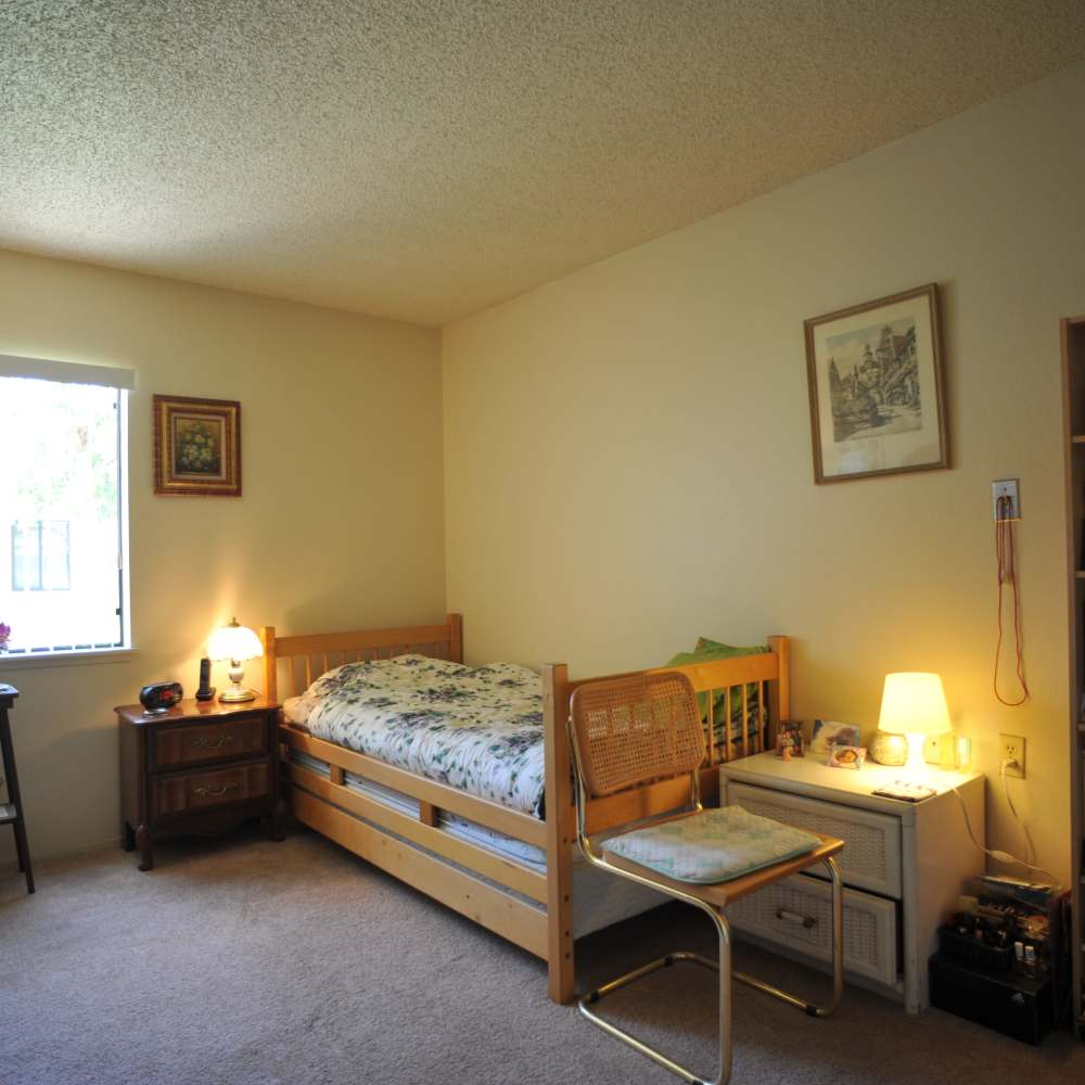 Twin bed and dresser in a carpeted bedroom at Glendora Gardens in Glendora, California