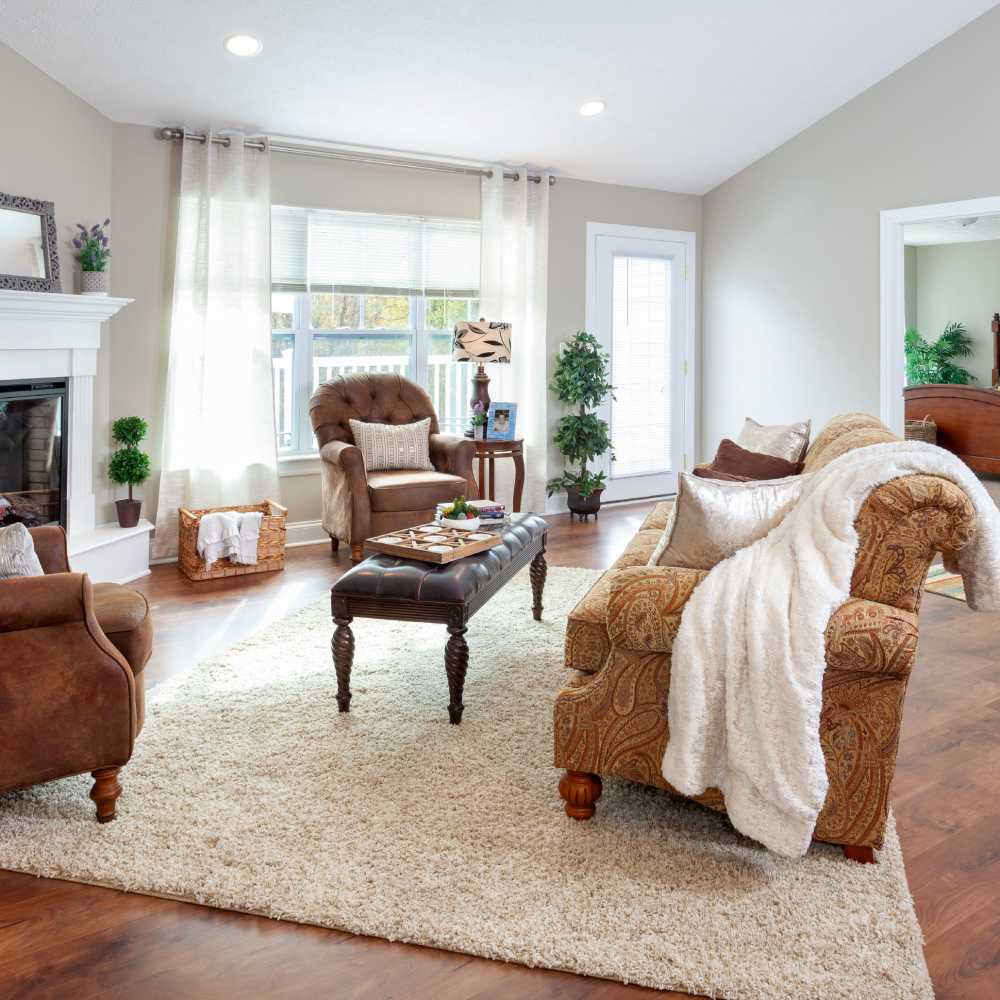 Cozy living room with fireplace, couches, and natural light streaming through windows at Fairways Villas II Apartments in Victor, New York