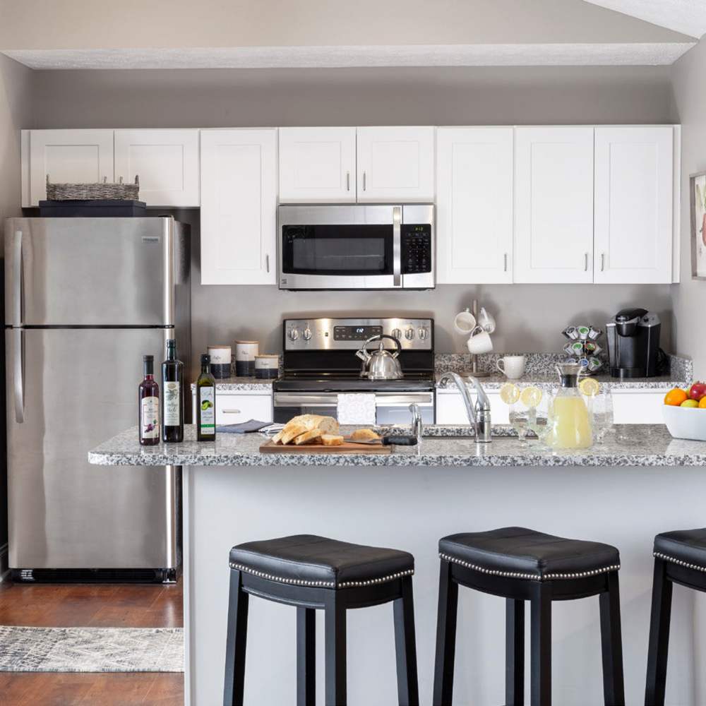 A modern kitchen with stainless steel appliances, and elegant granite countertops at Fairways Villas II Apartments in Victor, New York