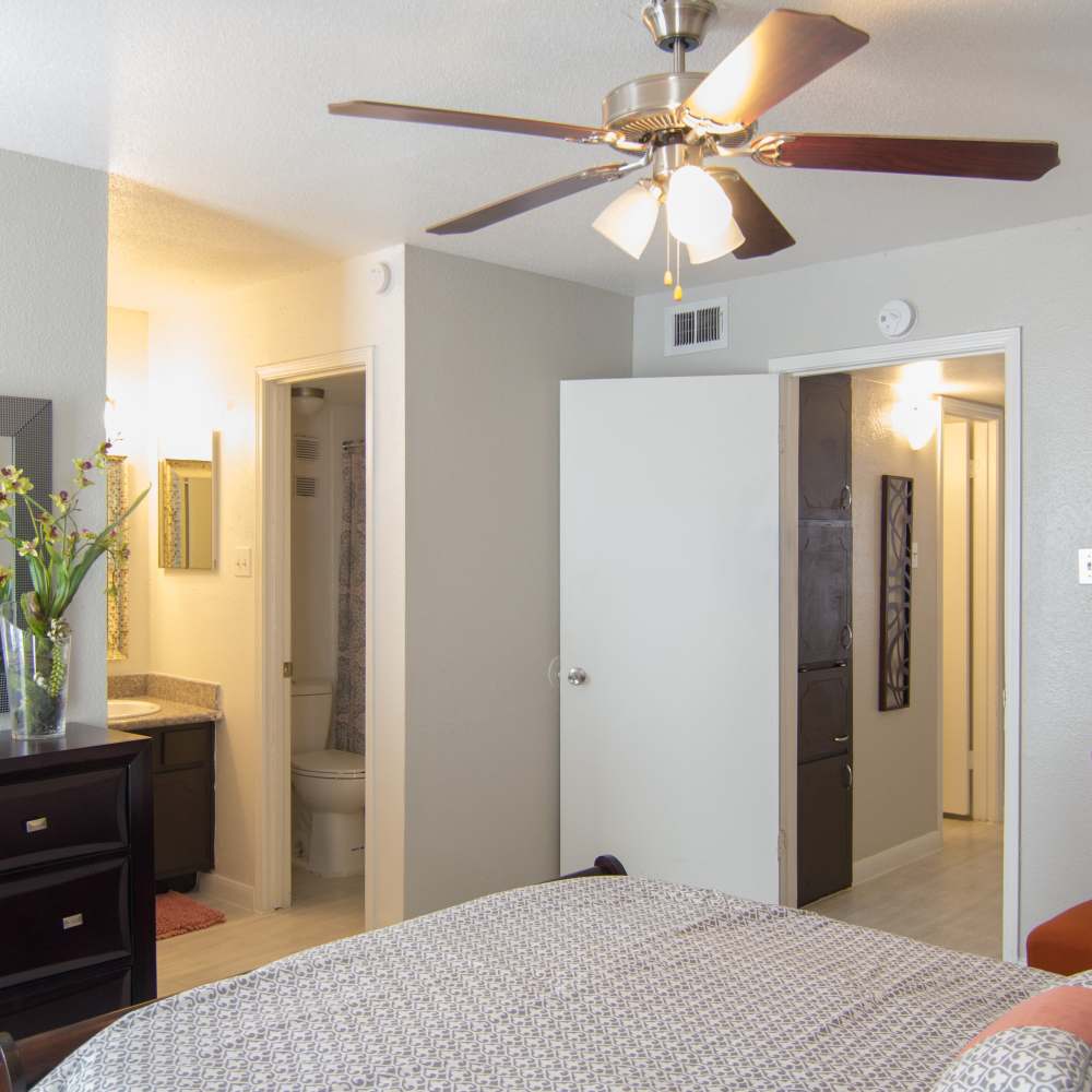Well-lit bedroom with ceiling fan , comfortable bed and attached bathroom at Villa Barcelona in Houston, Texas