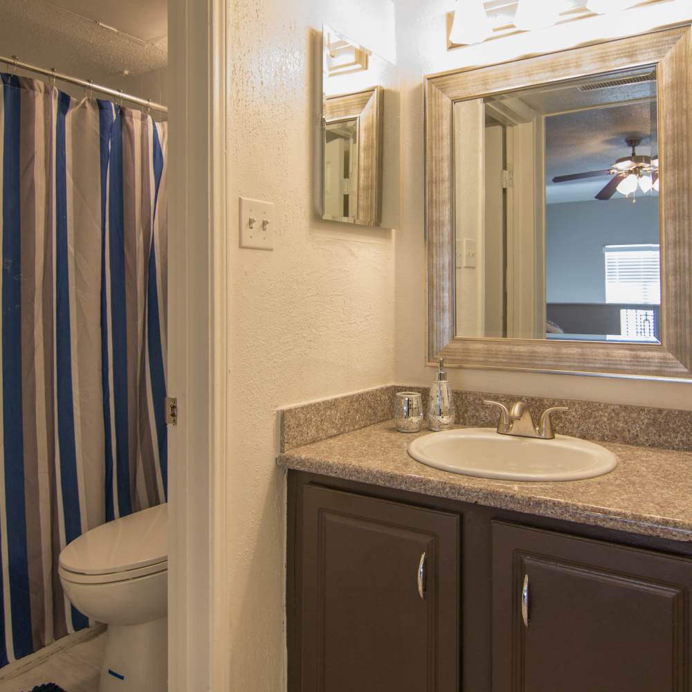 Bathroom with toilet, sink and a large mirror at Villa Barcelona in Houston, Texas