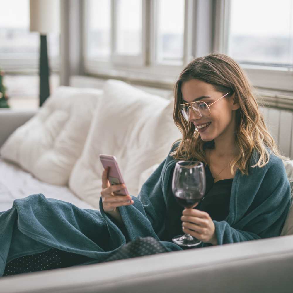 Resident relaxing on her couch with a glass of wine at Grand Oak Apartments in Largo, Florida