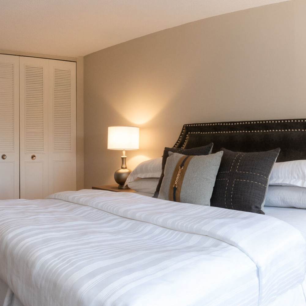 Large bed with bedside table and closet at The Pierre in Hackensack, New Jersey