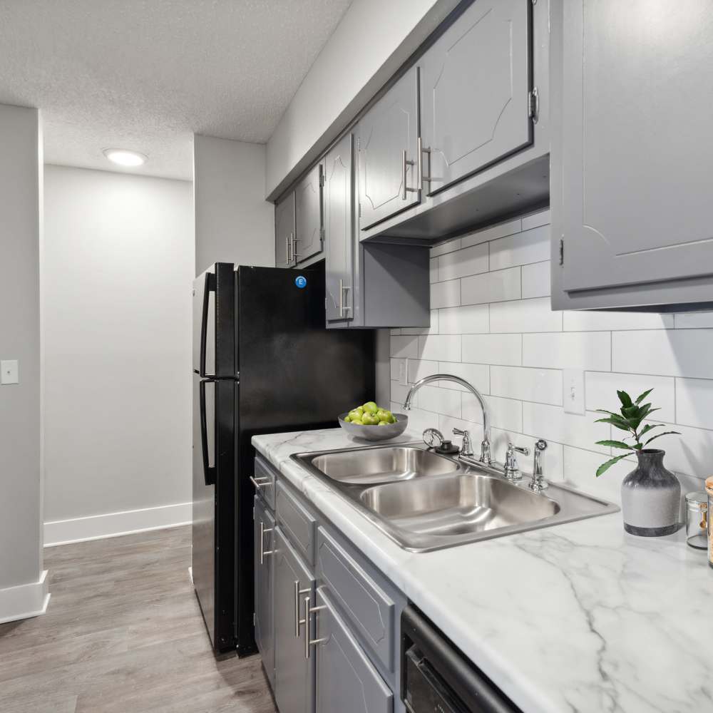 Cozy kitchen with white marble countertop, refrigerator and steel sink at Nottingham Apartments in Hendersonville, Tennessee