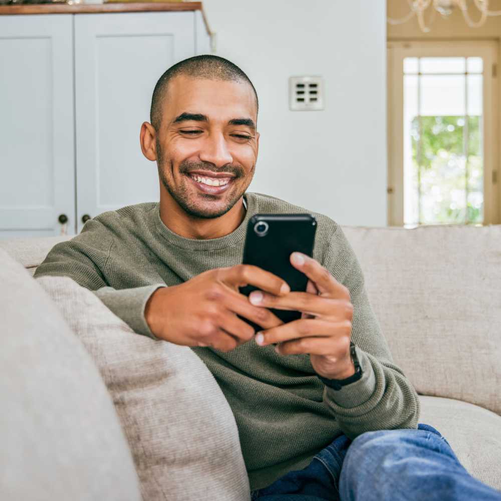 Resident texting from the couch of his living room at Park Manor in Lebanon, Oregon