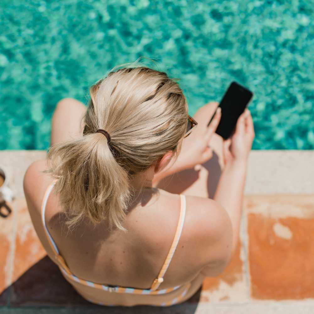 Resident on her phone by the pool Hacienda Commons in Pleasanton, California