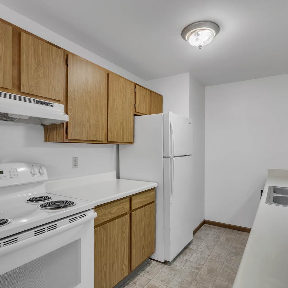 Apartment kitchen with white appliances like refrigerator and stove setup at Prairie Apartments in Salem,Wisconsin