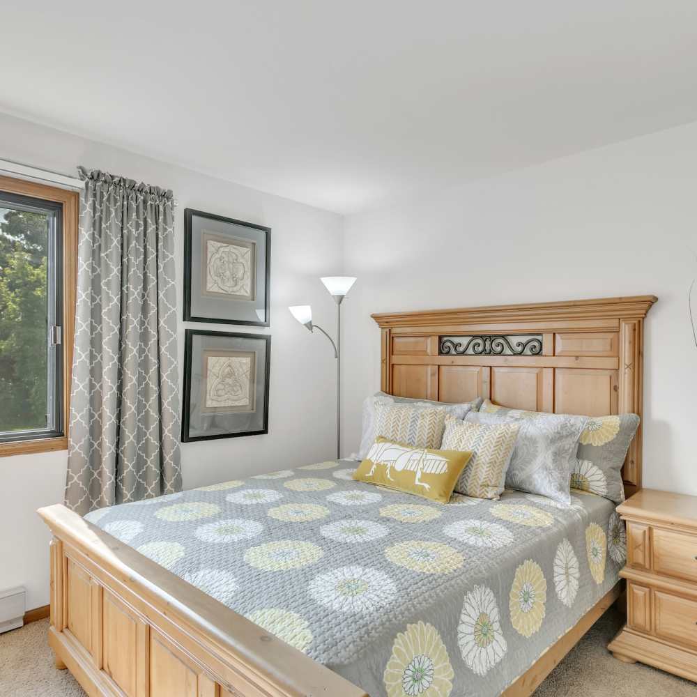 Pleasing bedroom with large bed and a window with a curtain at Prairie Apartments in Salem,Wisconsin