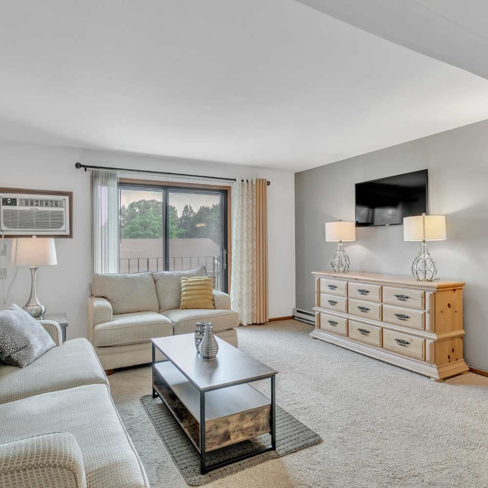 Apartment living room with wall-mount air conditioning and access to private balcony at Prairie Apartments in Salem,Wisconsin