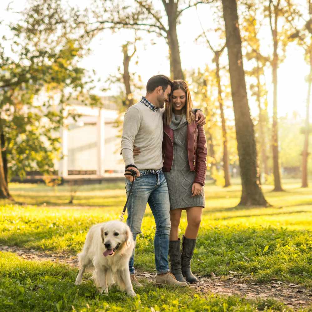 Happy couple walking with their dog in a park near À L'aise Hyde Park in Cincinnati, Ohio