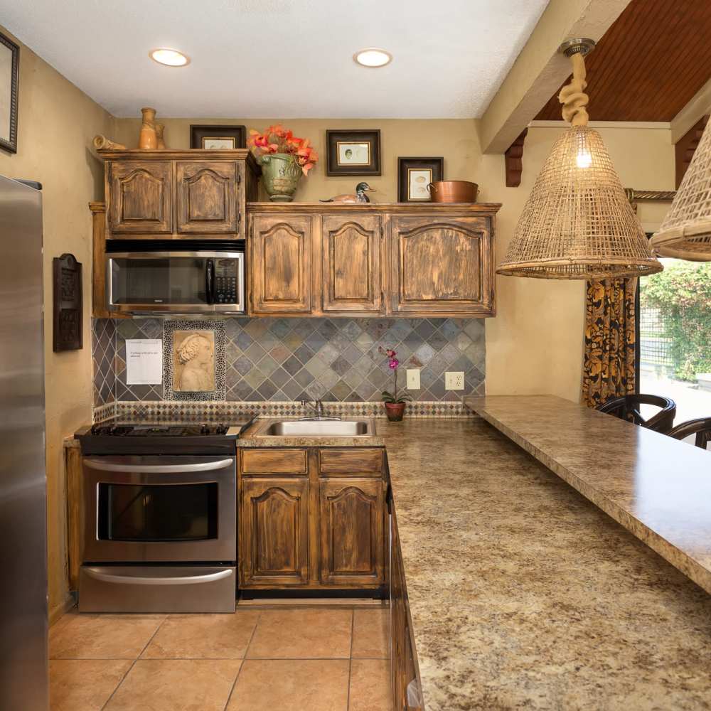 Community kitchen with granite countertops, wooden storage units and a refrigerator at The Arbors On Taylor in Montgomery, Alabama