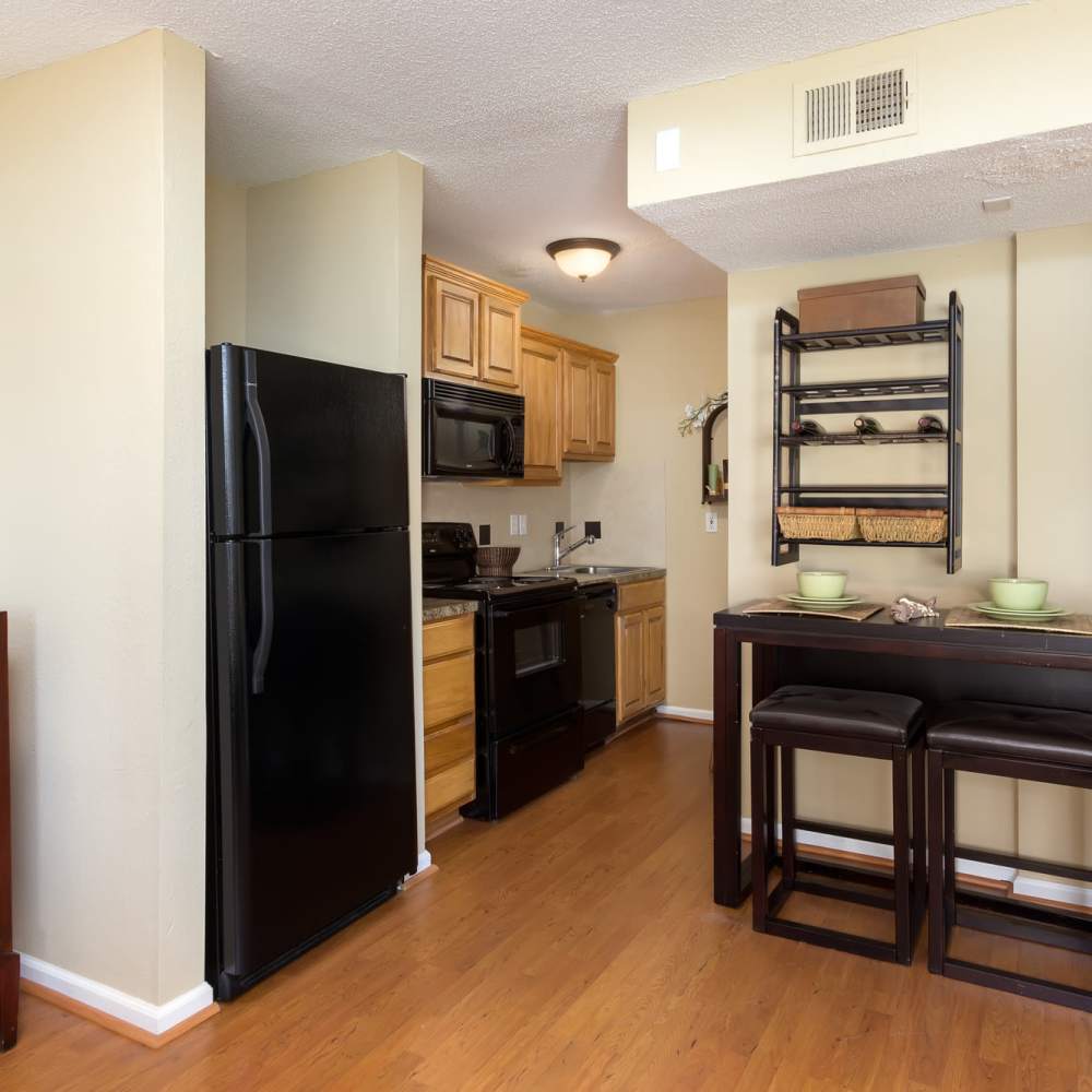 Kitchen with wooden cabinets, refrigerator and granite countertops at The Arbors On Taylor in Montgomery, Alabama