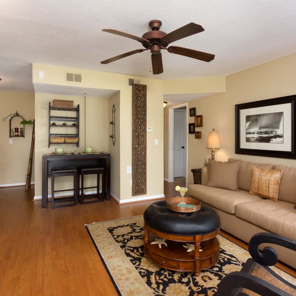 Spacious living room with a couch, coffee table and a door leading to the bedroom at The Arbors On Taylor in Montgomery, Alabama