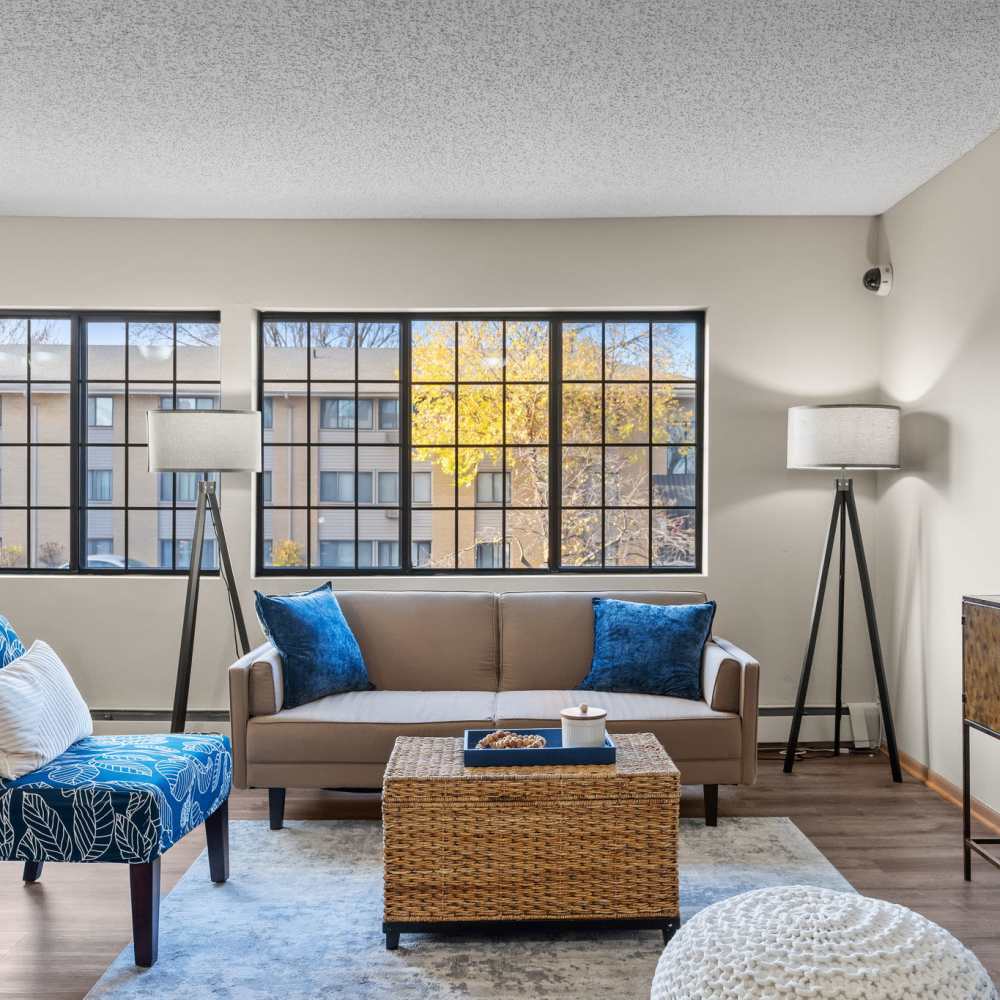 Well-lit living room with a comfortable couch and large windows at Granite Peaks in Minneapolis, Minnesota