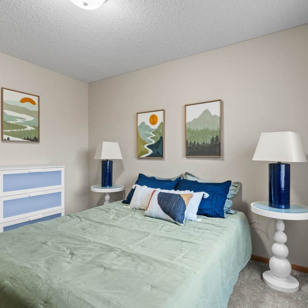Bedroom with a comfortable bed, side lamps and storage racks at Granite Peaks in Minneapolis, Minnesota