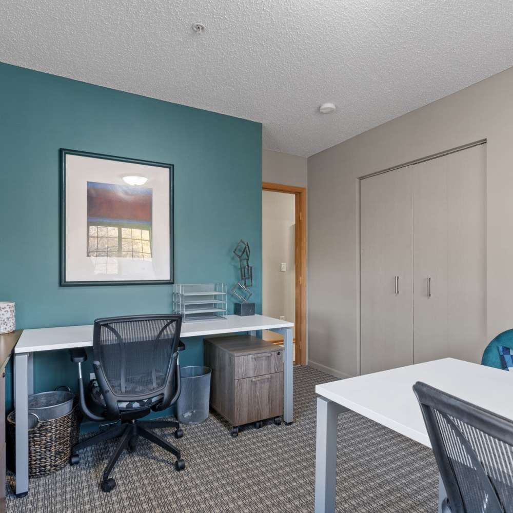 Community office room with a desktop, table and chairs at Granite Peaks in Minneapolis, Minnesota