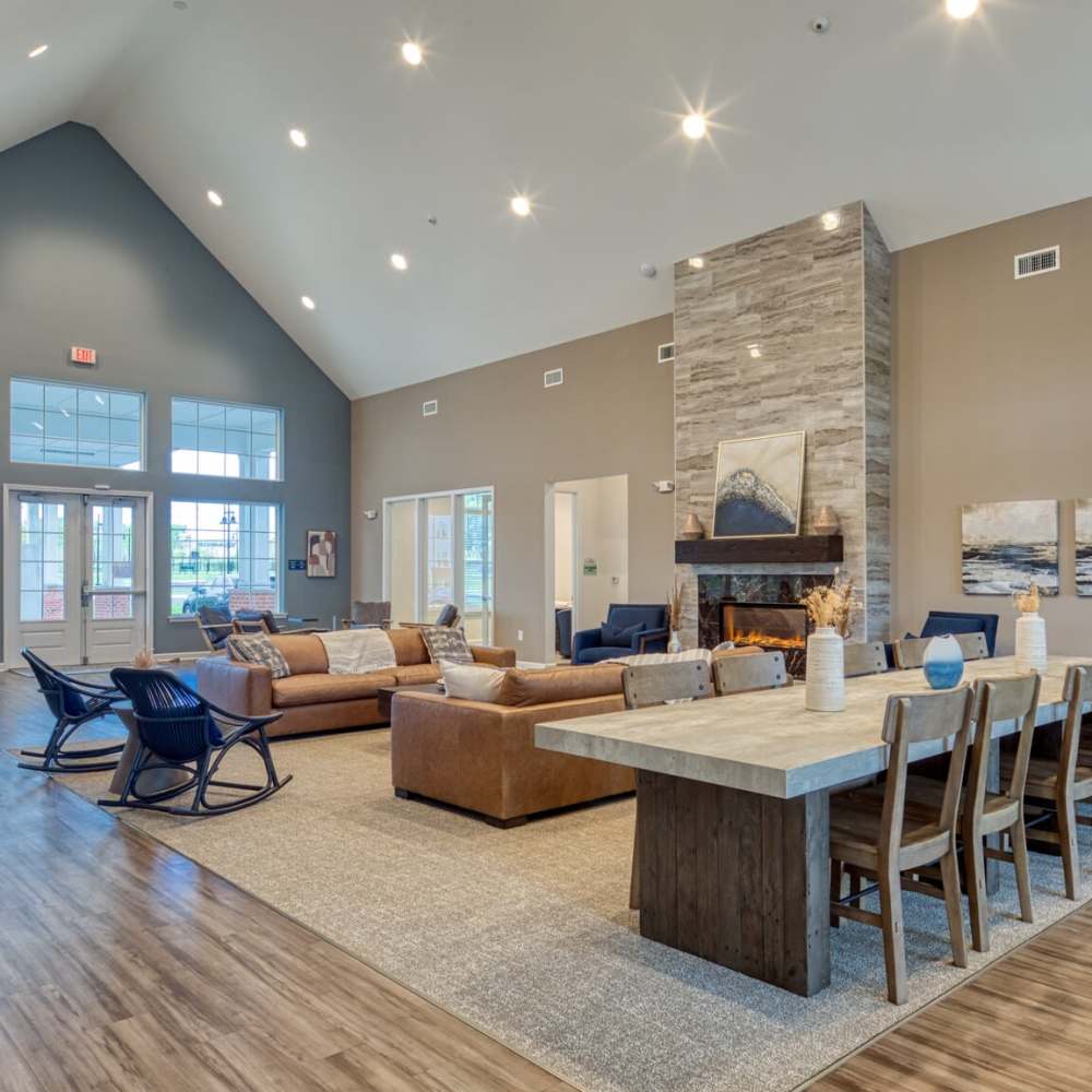 Spacious communal living room with high ceilings, seating area, fireplace, and dining table at Commonwealth Apartments in Midlothian, Virginia