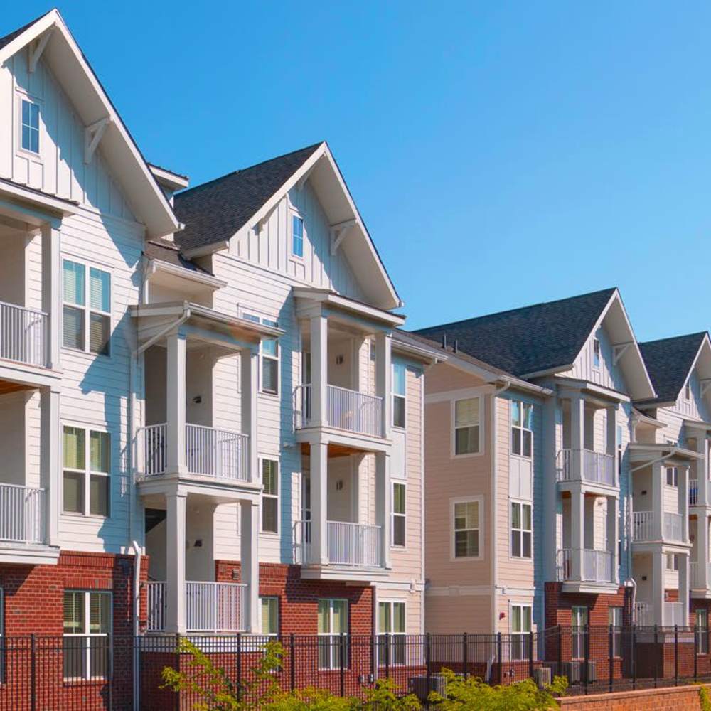 Row of modern apartment buildings with balconies and dark shingle roofs under a clear blue sky at Commonwealth Apartments in Midlothian, Virginia