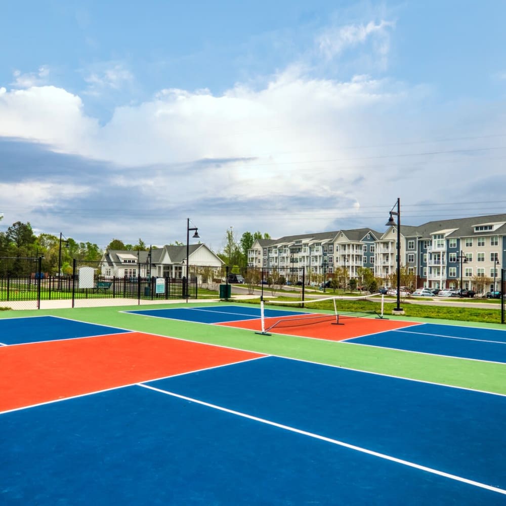 Colorful sports court with a basketball hoop, surrounded by apartment buildings and greenery at Commonwealth Apartments in Midlothian, Virginia