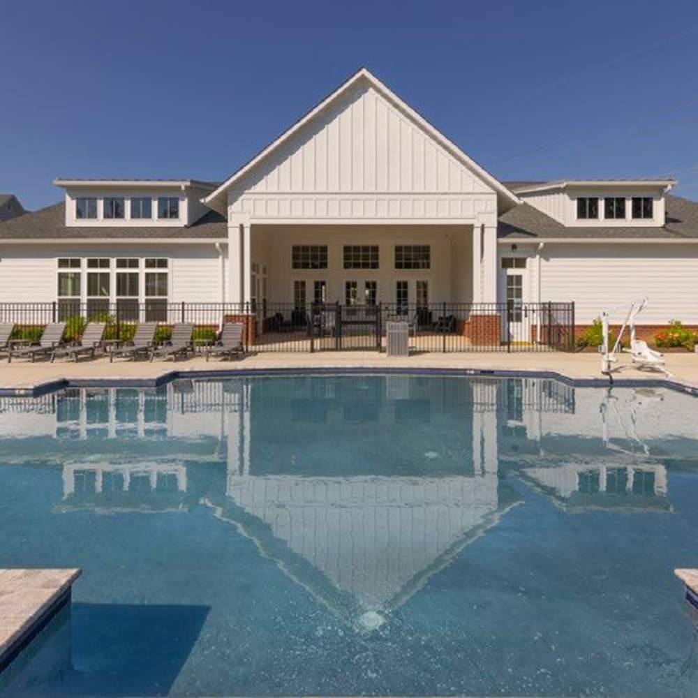 A white clubhouse with a gabled roof, seen from across a swimming pool at Commonwealth Apartments in Midlothian, Virginia