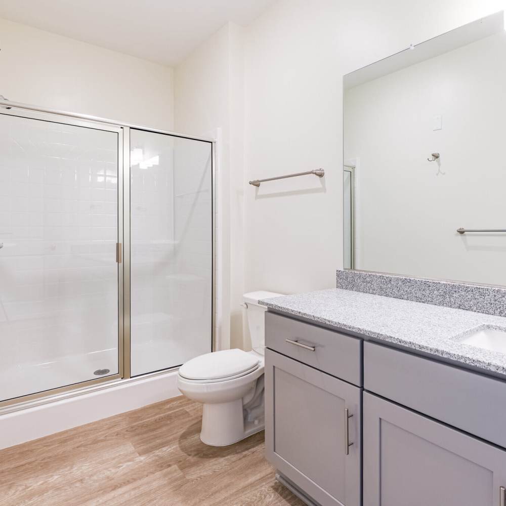Modern bathroom with a shower, toilet, and granite countertop at Commonwealth Apartments in Midlothian, Virginia